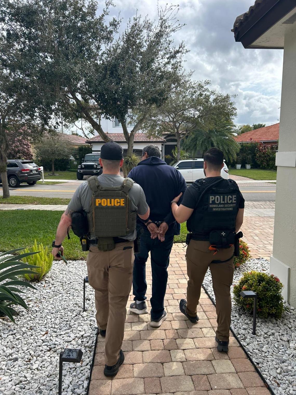Federal agents walk with a handcuffed man from a South Florida home Sunday, Jan. 26, 2025. The man, who was not identified, was one of several undocumented migrants rounded up by agents that weekend.