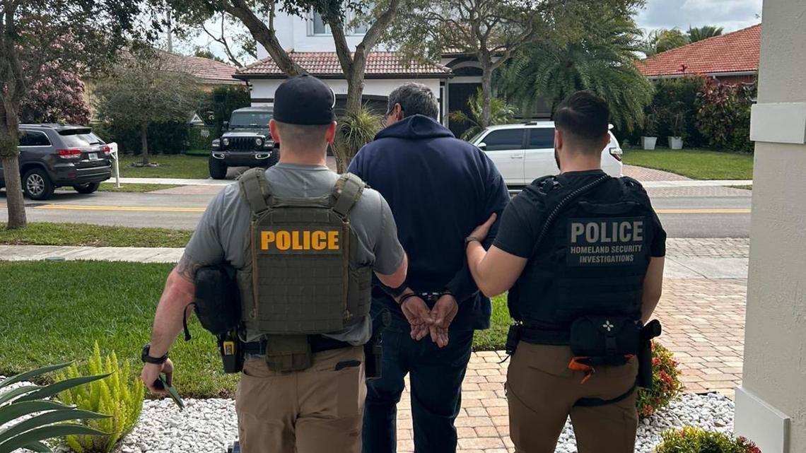 Federal agents walk with a handcuffed man from a South Florida home Sunday, Jan. 26, 2025. The man, who was not identified, was one of several undocumented migrants rounded up by agents over the weekend.
