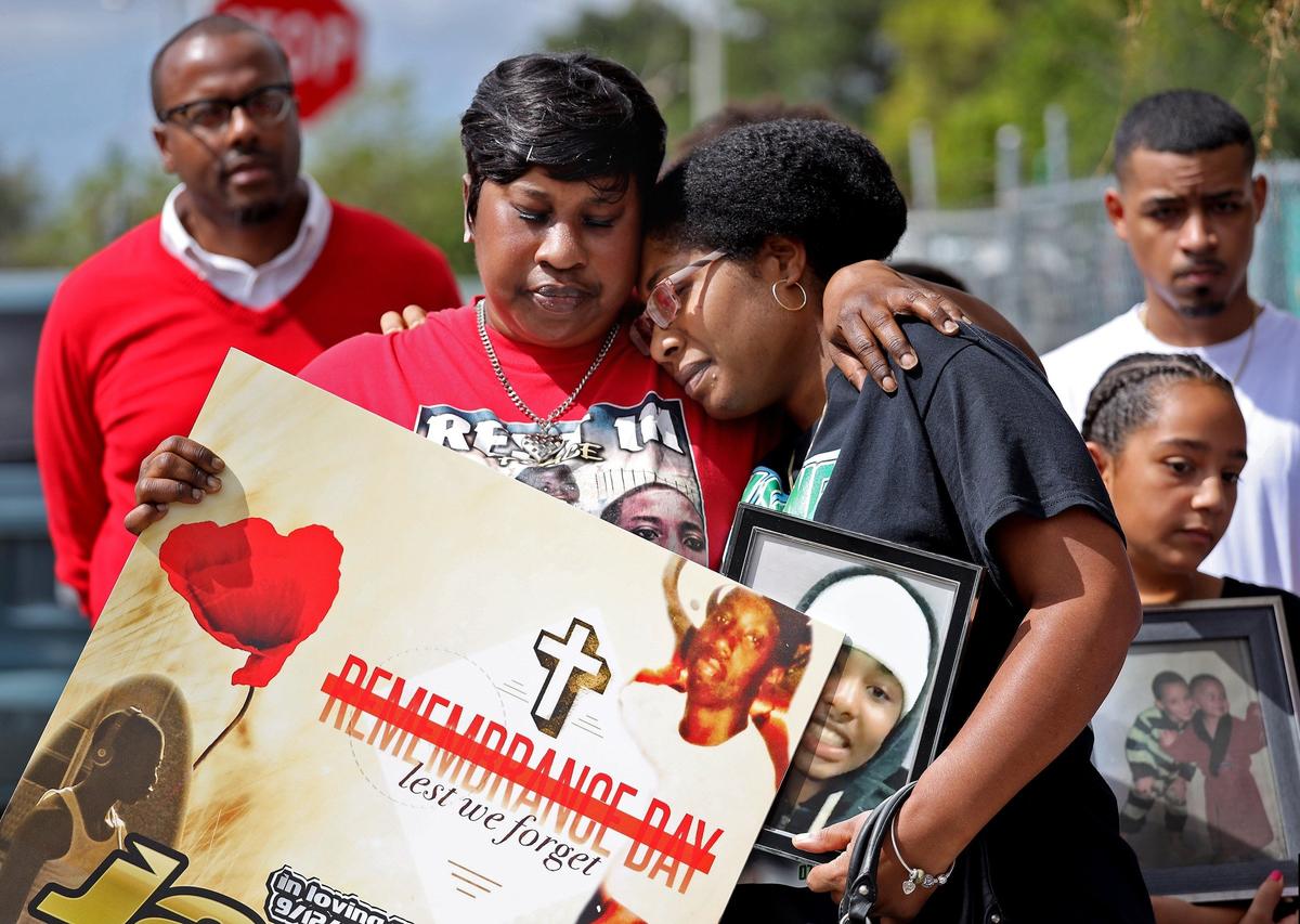 Grieving mothers Debryon Murray, 47, left, consoles Omorose Butler, 35, as members of Florida Parents of Murdered Children, concerned citizens, and local police officers stood together in remembering the first anniversary of the Marjory Stoneman Douglas mass shooting in solidarity with Parkland Kids, Pray for Parkland Parents on Thursday, Feb. 14, 2019. Annaliese Balbona, 11, stands on the right holding a picture of her brother Isaiah, who was killed by gun violence.