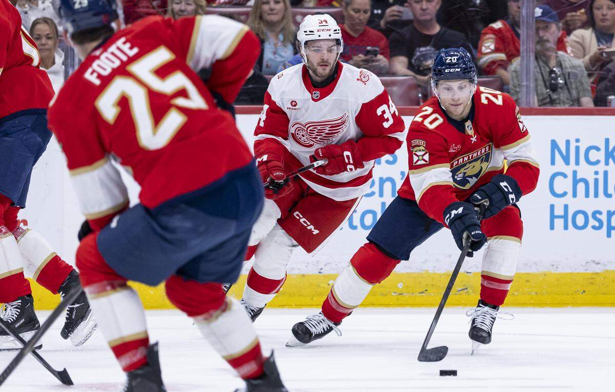 Florida Panthers defenseman Mike Benning (20) skates with the puck as Detroit Red Wings left wing Carter Mazur (34) defends in the first period of their NHL game at the Amerant Bank Arena on Wednesday, April 15, 2026, in Sunrise, Fla.