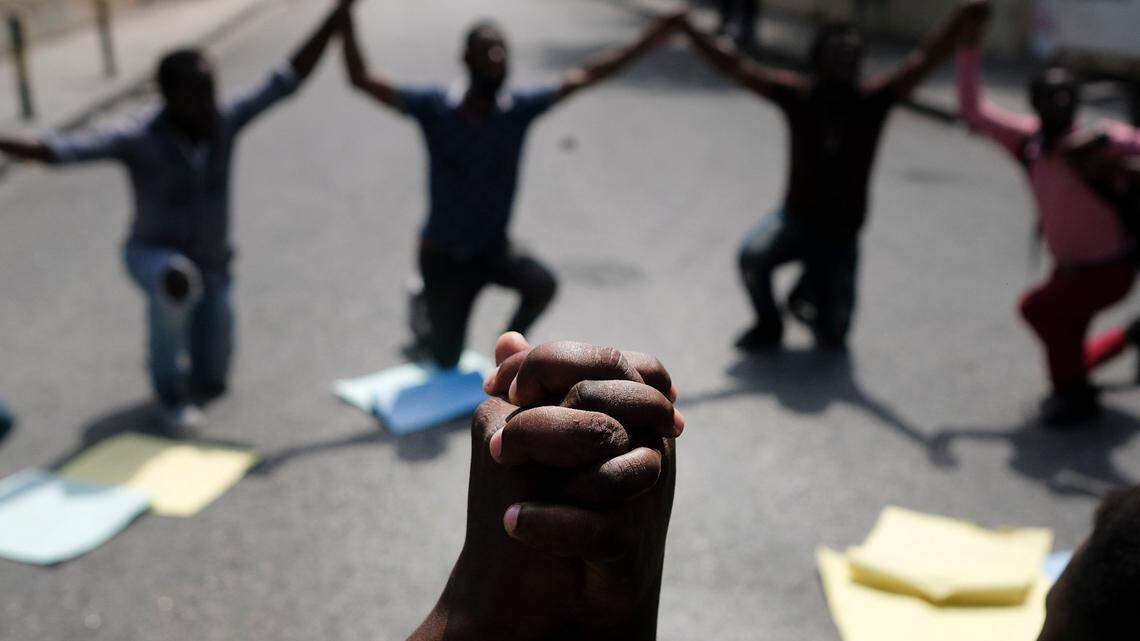 People kneel outside the Justice Ministry to demand the resignation of then Acting Justice Minister Liszt Quitel and protest kidnappings, during a strike in Port-au-Prince, Haiti, Tuesday, Oct. 26, 2021. Worker unions along with residents called for a general strike to demand the end of kidnappings, violence and insecurity in the streets.