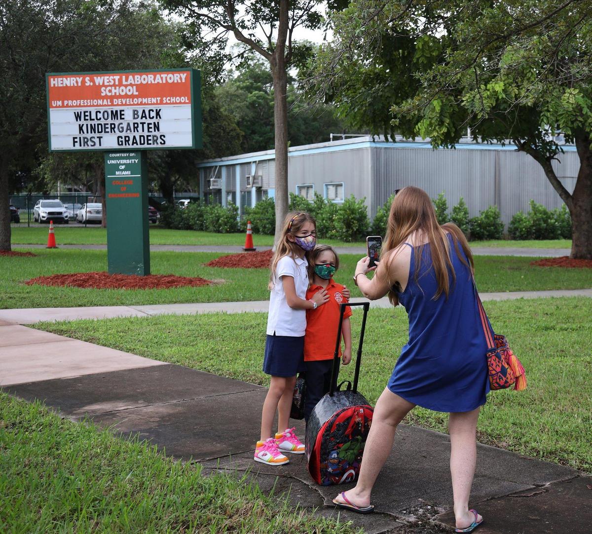 A parent takes a photo of her children as Henry S. West Laboratory School welcomed kindergartners and first-graders back to classrooms on Monday, Oct. 5, 2020. Classrooms reopened for the first time since the COVID-19 pandemic closed schools earlier in the year.