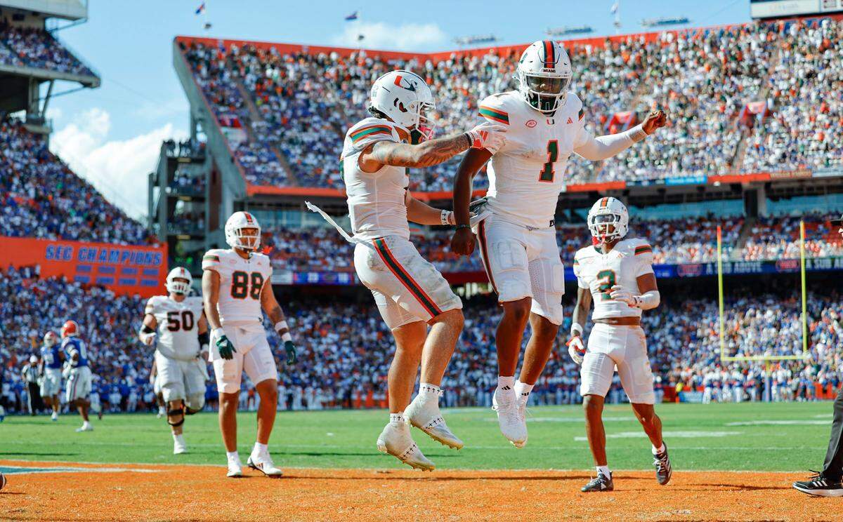Miami Hurricanes wide receiver Xavier Restrepo (7) and quarterback Cam Ward (1) celebrate in the end zone after Restrepo scores on a pass by Ward during the second quarter of an NCAA college football game at Ben Hill Griffin Stadium in Gainesville, Florida, on Saturday, August 31, 2024.