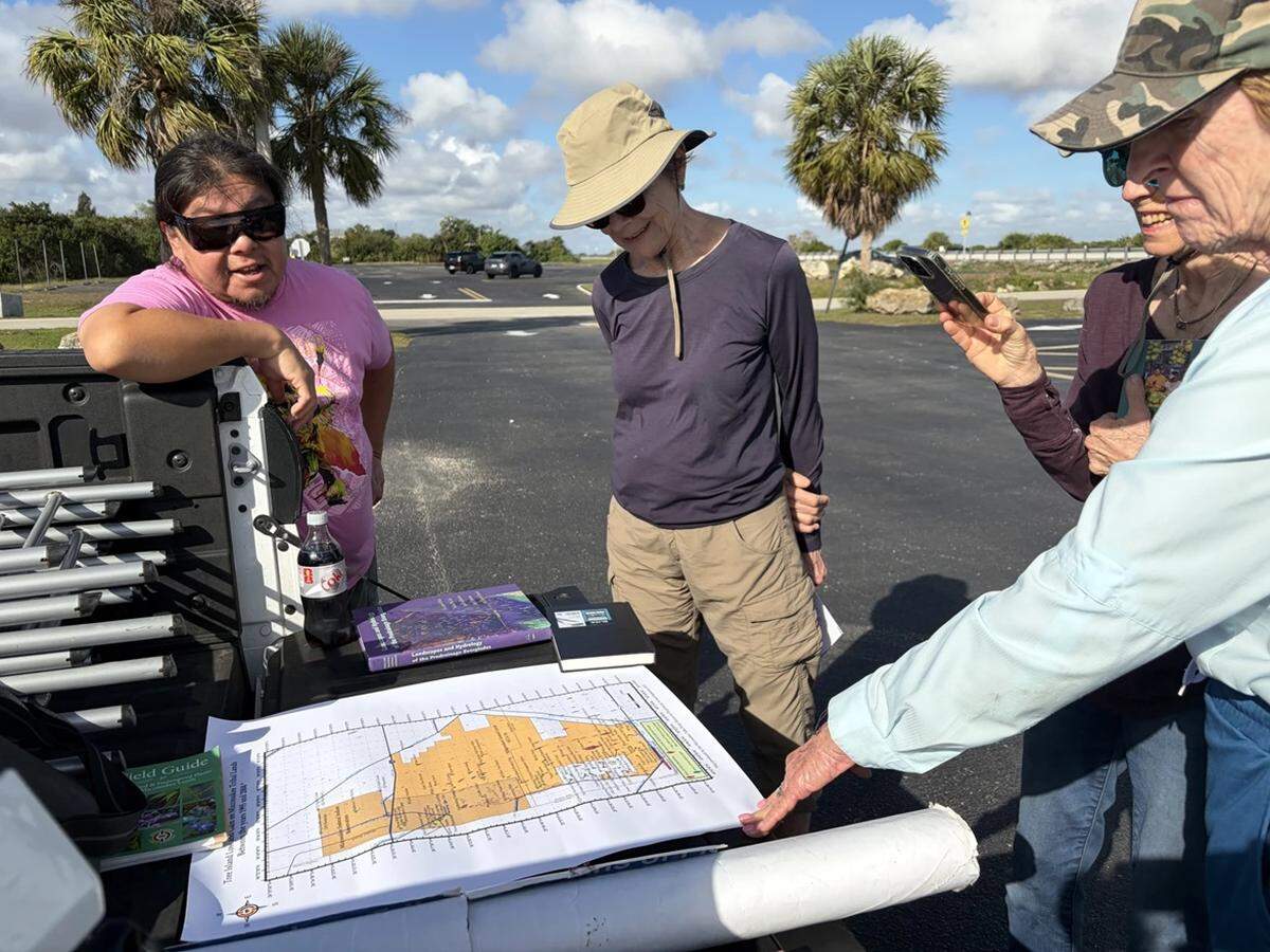 Houston R. Cypress, left, co-founder of the Love the Everglades Movement, and Dale Andree, center, co-founder of A Walk Through Our Neighborhoods, review a map of Miccosukee land with walking-tour participants.