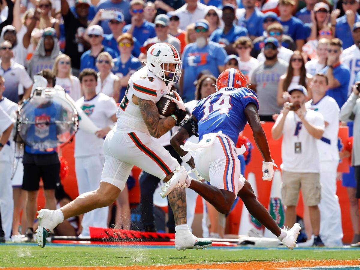 Miami Hurricanes tight end Cam McCormick (84) runs with the football against Florida Gators defensive back Jordan Castell (14) during the first half of an NCAA college football game at Ben Hill Griffin Stadium in Gainesville, Florida, on Saturday, August 31, 2024.