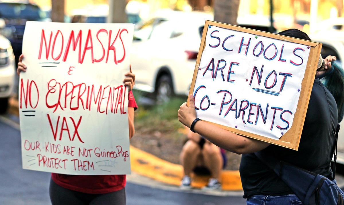 Antimask supporters hold signs while inside the Broward County School Board holds a hearing to determine if they will impose a mask mandate for the upcoming school year, Fort Lauderdale, Florida, August 10, 2021.