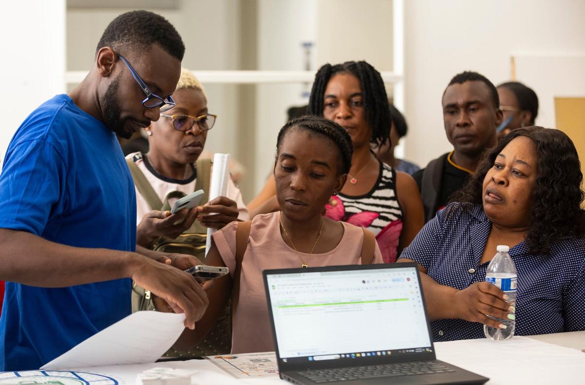 Sammy Lamy, director de Jobs4Us, ayuda a las personas a registrarse en una feria de recursos comunitarios en el Distrito de Innovación de Magic City el viernes 31 de mayo de 2024 en Miami.