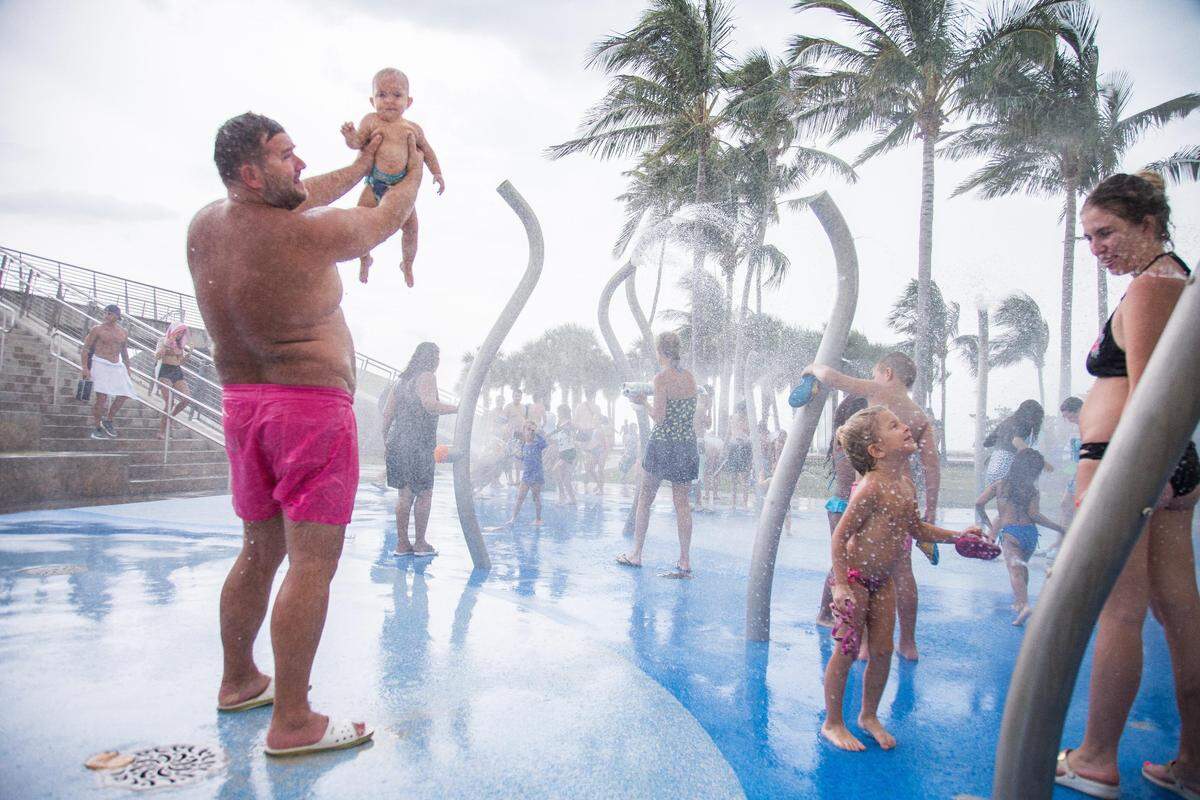 Alex Gavrilov, left, and his wife, Kate, cool down with their children from the heat after a day at the beach at South Pointe Park in Miami Beach on July 22, 2018.