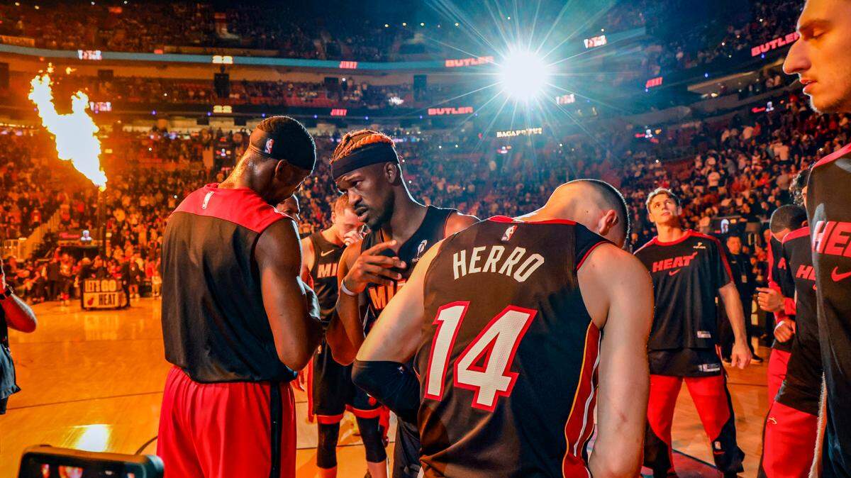 Miami Heat center Bam Adebayo (13) and forward Jimmy Butler (22) meet on the court with teammates during introductions before the start of an NBA basketball game against the Oklahoma City Thunder at Kaseya Center in Miami on December 20, 2024.
