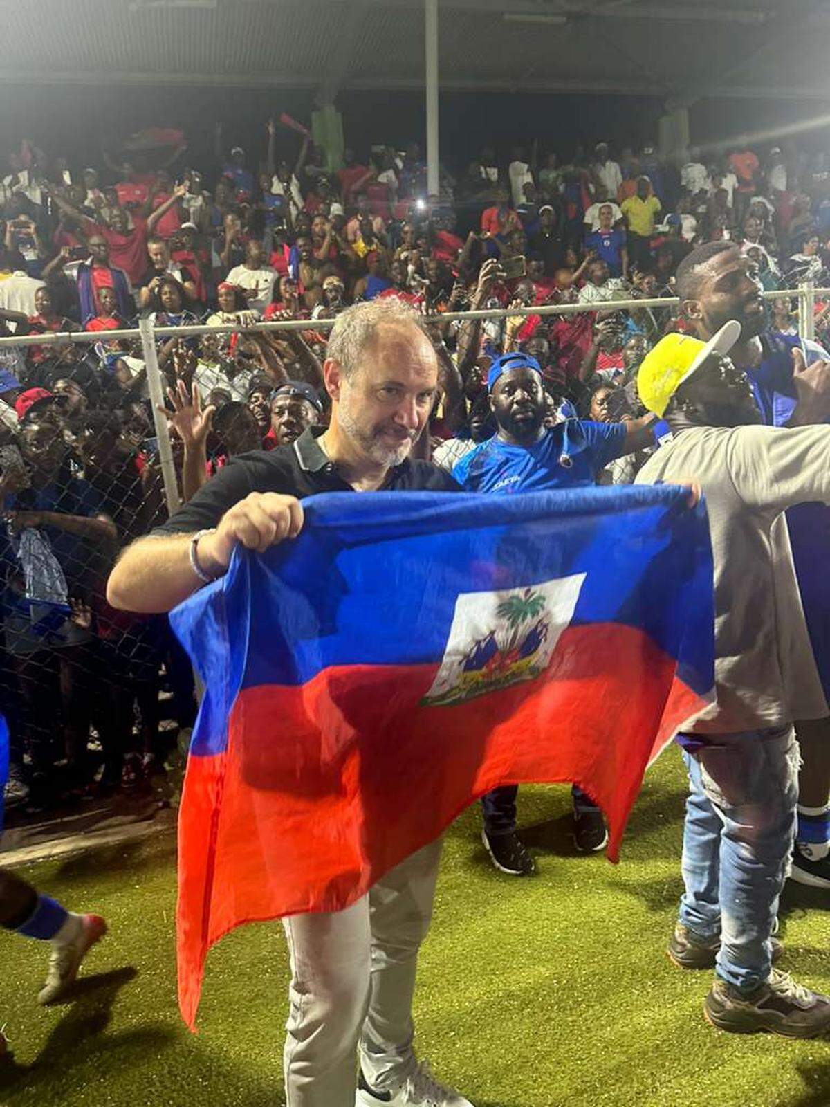 Haiti national soccer team coach Sebastien Migne celebrates with the Haitian flag after the team qualified for the World Cup for the first time since 1974 with a 2-0 win over Nicaragua in Curacao on Nov. 18, 2025.