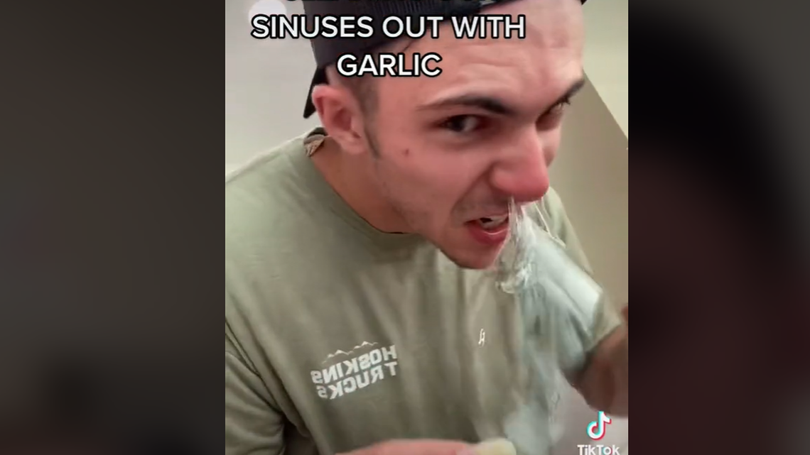Screengrab of a TikTok video showing users stick garlic cloves up their nostrils to help clear congestion.