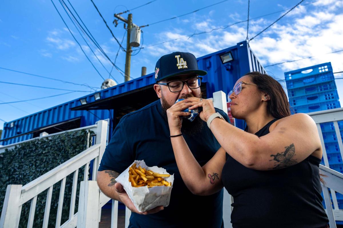 Laura “Lala” Budnechky feeds her husband Jeff a burger from Lala’s Burgers at Lincoln’s Beard Brewing Co. in Miami.