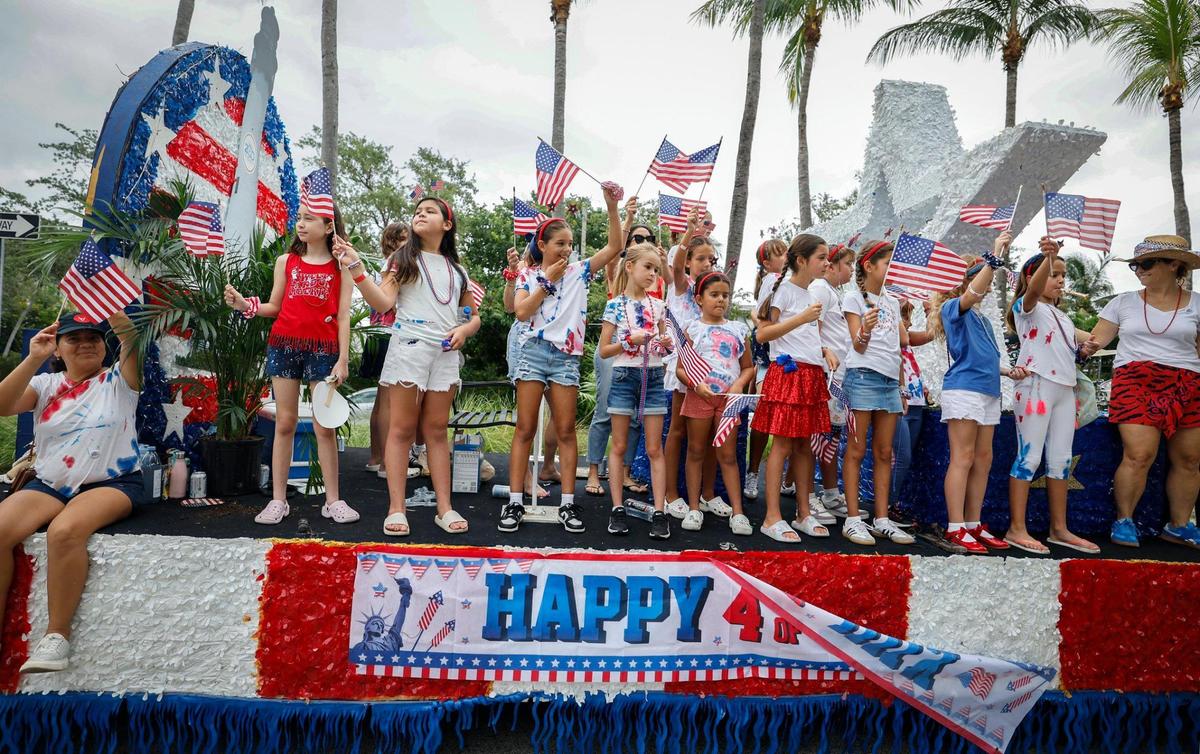 Children wave the American flag from their parade float as residents, family and friends celebrate Independence Day during the 66th Annual Key Biscayne Fourth of July Parade on Key Biscayne, Florida on Friday, July 4, 2025.