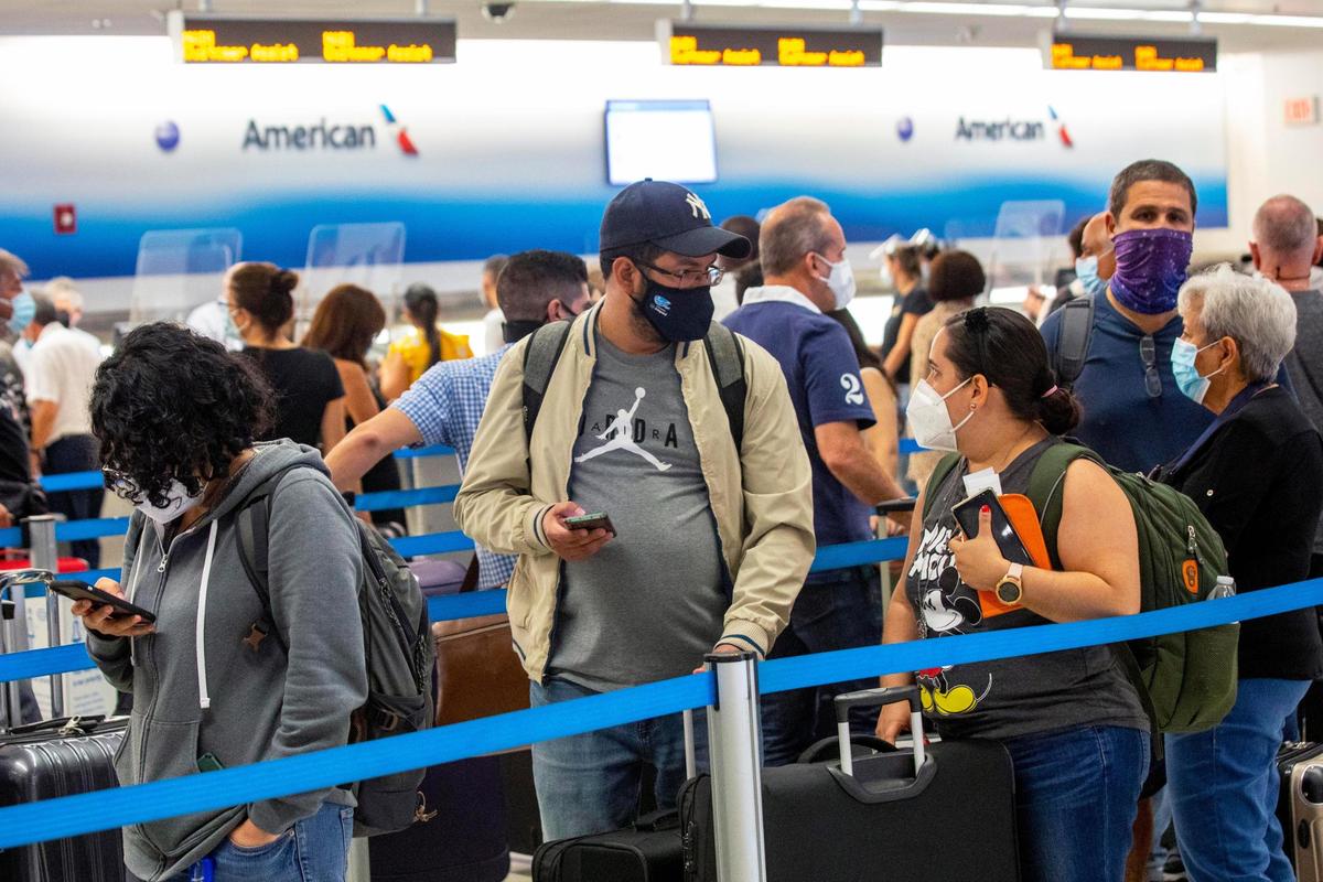 Travelers wait in line before checking in their luggage for their international flight at Miami International Airport in Miami, Florida, on Monday, June 7, 2021.