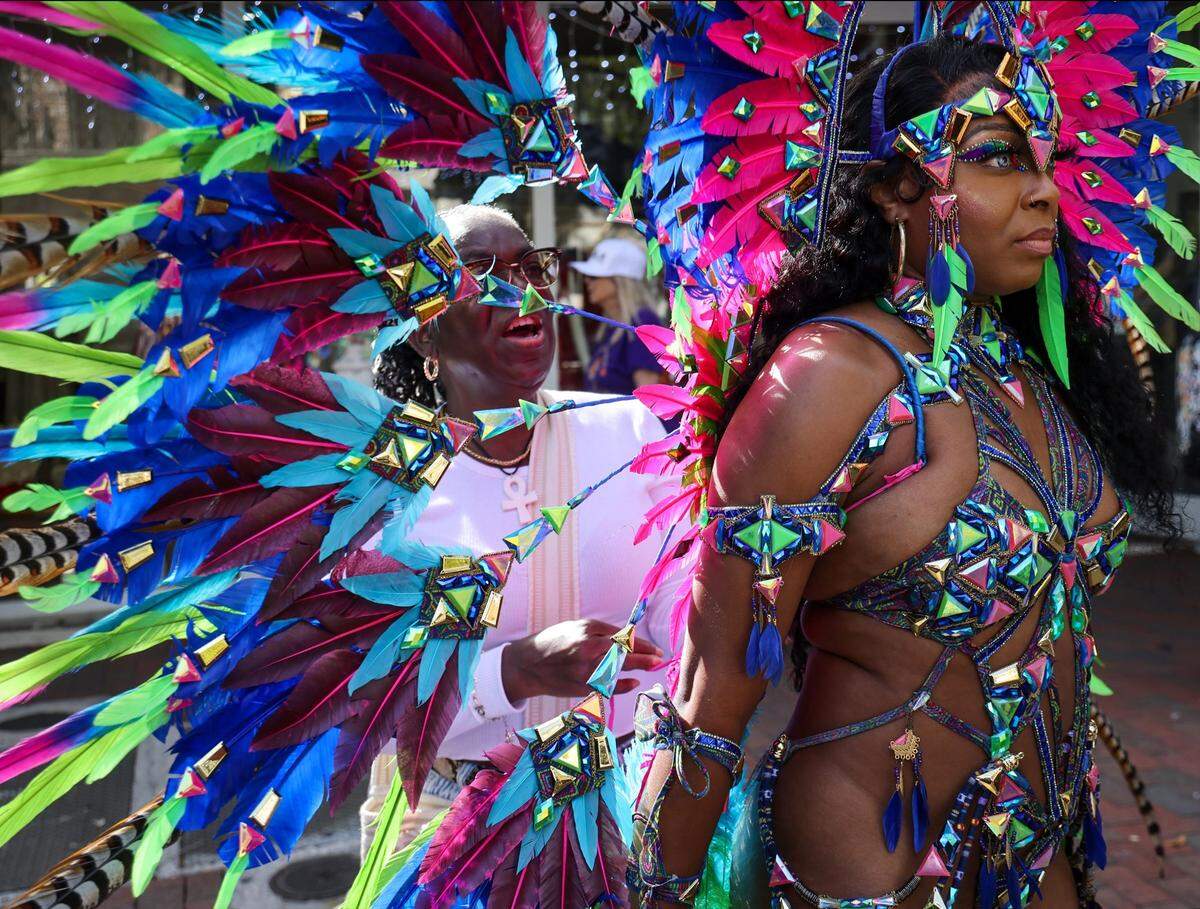 Tammie Brooks, left, adjusts the costume of Racine Bonelli, right, while prepping for the 41st Annual King Mango Strut Parade.