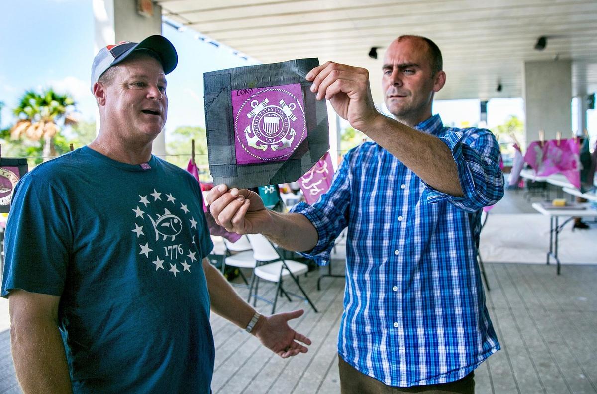 Drew Matott, right, Director of the Peace Paper Projects shows Torin Zielenski, left, retired from the U.S. Coast Guard one of the silkscreens produced by veterans in his class at the PAMM in Miami on Thursday, August 2, 2018