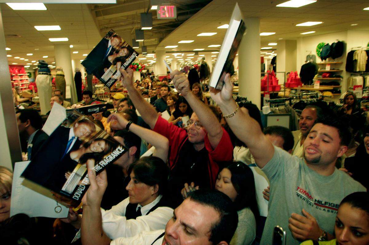 Crowds of waiting people wave their books and other items, wanting to get them autographed by Donald Trump as he got up to leave from his appearance Friday, Dec. 10, 2004, at Burdines-Macy’s in Dadeland. He left without signing the books. Trump came to Miami to promote his new perfume and line of men’s suits.