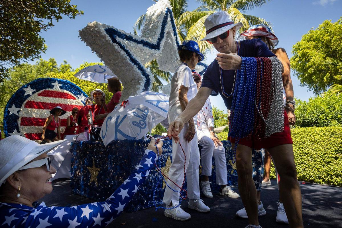 Laura Marmol, right, with Active Seniors on the Key, hands out beads to Ivette Yrizarry, from the Key Biscayne Women’s Club, before the Fourth of July parade along Crandon Boulevard.