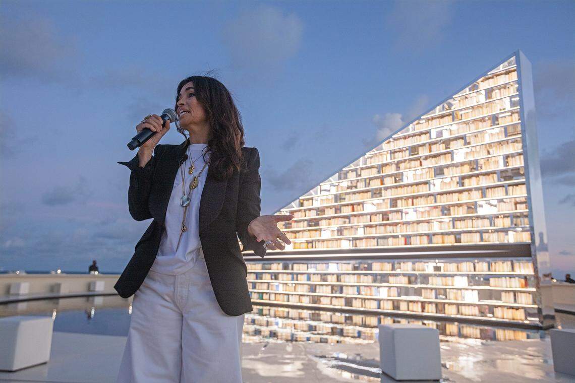 Miami Beach, Florida, December 1, 2025 - Es Devlin speaks in front her kinetic sculpture titled Library of Us located on the beach behind the Faena Hotel in Miami Beach, Florida. A luminous, participatory installation, The Library of Us by Es Devlin is a 50-foot-wide rotating triangular bookshelf containing 2,500 books that have shaped the artist's life and practice. The installation will be on display from December 2 thru Dec 7, 2025 behind the Faena Hotel in Miami Beach, Florida.