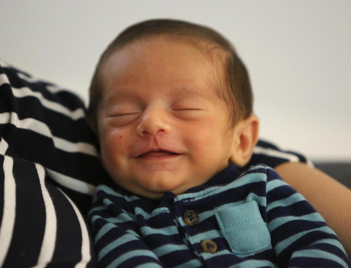Baby Alan smiles while being held by his mom, Naiviv Perera Morales at the Miami Springs cottage they are renting from a family member.