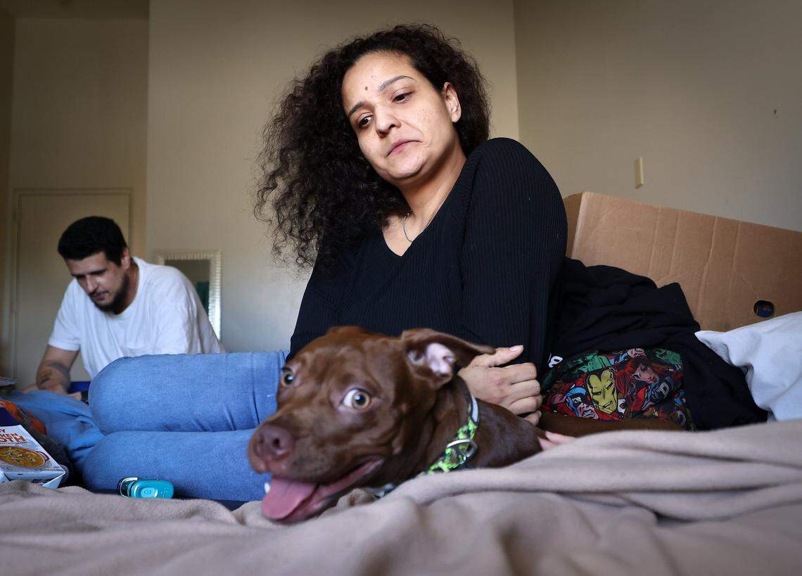 Michael Torres, left, Diana Olivo, right, and family members have been sharing a motel room for the last six months. She does not know how long they'll be able to afford to stay there, and he reflects on the challenges of being unsheltered as they try to keep their family intact, including caring for their beloved pet, “Hazel,” on Wednesday, February 25, 2026, in Miami-Dade, Florida.