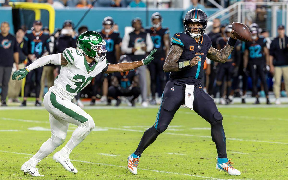 Miami Dolphins quarterback Tua Tagovailoa (1) prepares to throws under pressure from New York Jets cornerback Michael Carter II (30) during the first half of an NFL game Monday, Sept. 29, 2025, at Hard Rock Stadium in Miami Gardens, Fla.