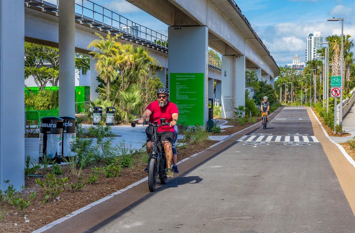 Cyclists ride past the Vizcaya Metroral Station on the Underline urban trail and linear park.