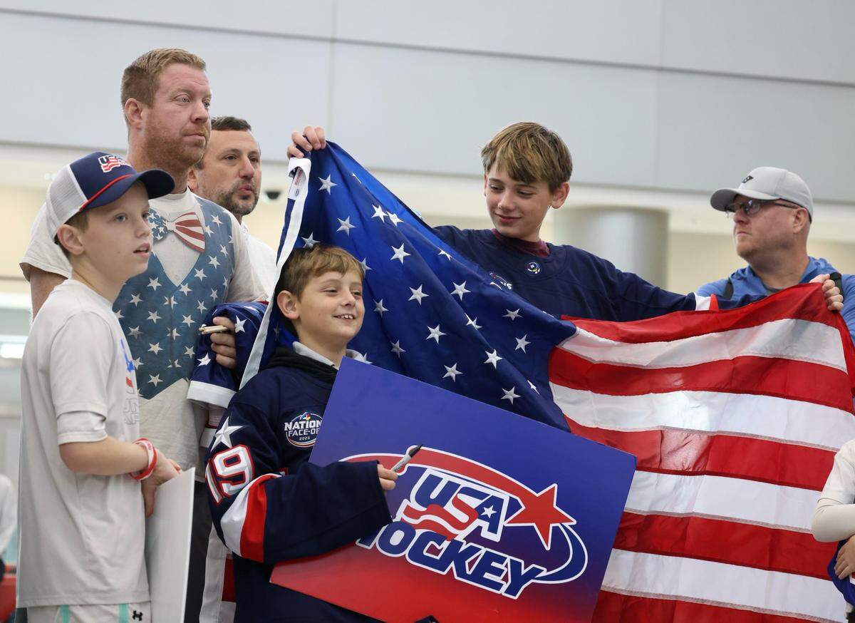 From left, Grant Vlaardingerbroek, his father Matt Vlaardingerbroek, Jason Vishio and his sons, Brodhi and Brecken Vishio, hold a flag as they wait for the United States men's hockey team to arrive at Miami International Airport on Monday, Feb. 23, 2026, in Miami. The team flew in from Milan after defeating Canada to win the gold medal at the 2026 Winter Olympics in Milano-Cortina, Italy.