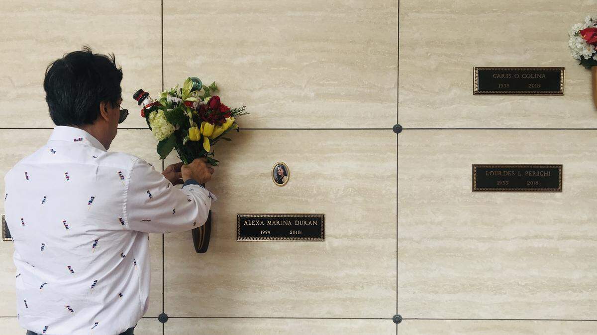 Orlando Duran places flowers at his daughter’s resting place.