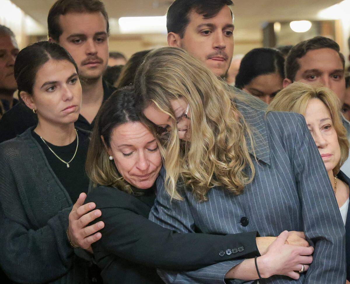 Surrounded by family, friends, and supporters, Cecilia Pino, center, the wife of real estate broker George Pino, holds the hand of her daughter, Carolina Pino, right, as Pino’s attorney gives a brief statement in the hallway near Courtroom 4-3 at the Richard E. Gerstein Justice Building on Thursday, November 21, 2024, in Miami, Florida.