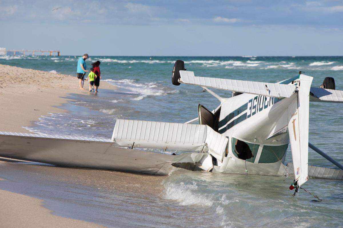 Beachgoers stand close to the water line next to a small plane that crashed on 108 block in Haulover Beach, on December 24th., 2018. The plane left at 1 pm from Fort Lauderdale with 4 passengers, at 1:33 pm due to engine malfunction had to land. All 4 passengers had no injuries.