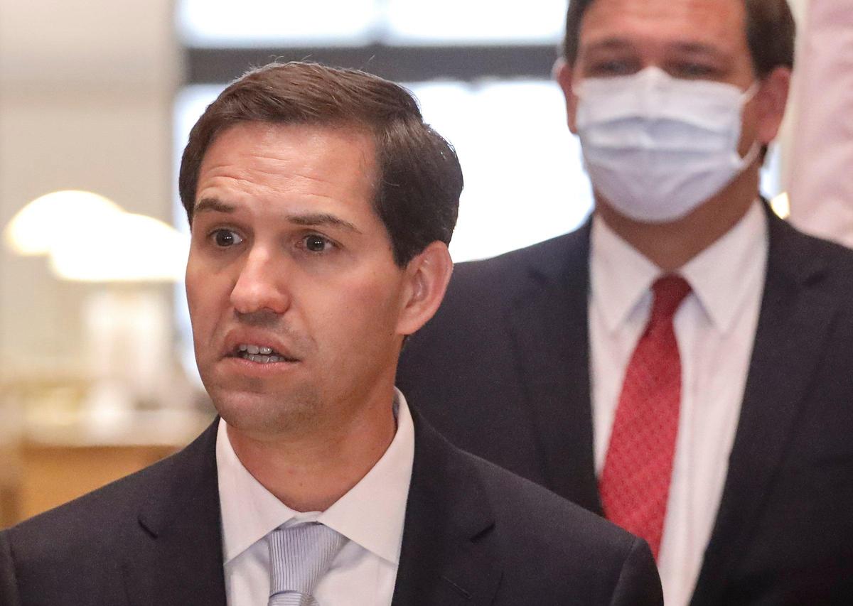 John Couriel, left, an attorney with Miami firm Kobre & Kim, gives his remarks after being appointed by Gov. Ron DeSantis, right, to the Florida Supreme Court during DeSantis’ press conference on Monday, May 26, 2020 inside the Miami-Dade Public Library main branch in downtown Miami, Florida.