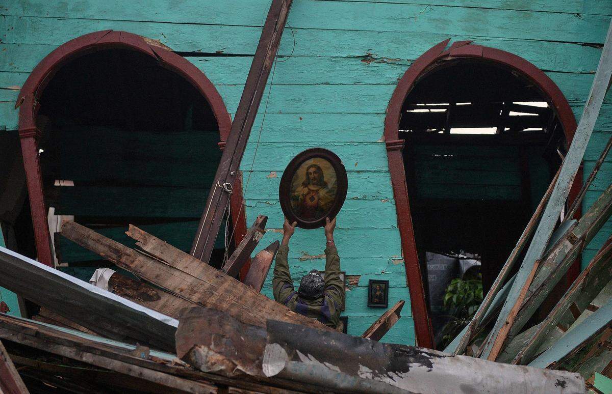 A man salvages an image of Jesus Christ from a destroyed building, after the passage of a rare and powerful tornado in Havana on Monday Jan. 28, 2019.
