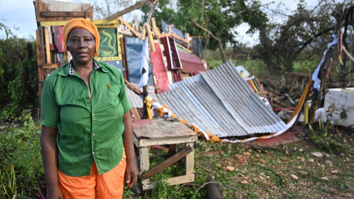 Celia Coke stands next to her shop, destroyed after the passage of Hurricane Melissa in the Wilton district of St. Elizabeth, Jamaica on October 29, 2025. Hurricane Melissa ripped up trees and knocked out power after making landfall in Jamaica on October 28, 2025 as one of the most powerful hurricanes on record, inundating the island nation with rains that threaten flash floods and landslides. 