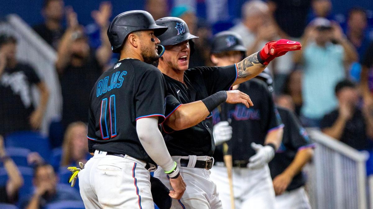 Miami Marlins teammates Peyton Burdick (86) and Miguel Rojas (11) react to scoring runs off a Joey Wendle (18) double during the sixth inning of an MLB game against the Los Angeles Dodgers at loanDepot park in the Little Havana neighborhood of Miami, Florida, on Friday, August 26, 2022.