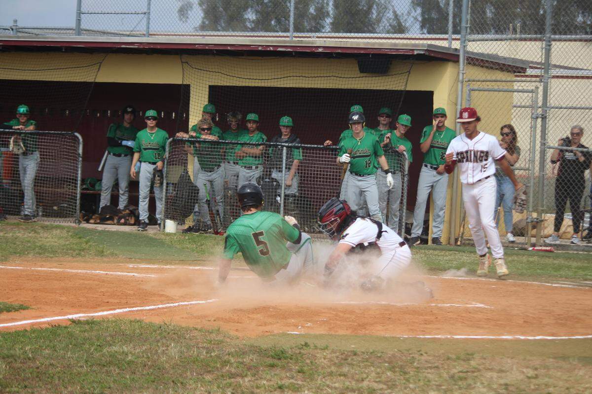Westminster Christian’s Ethan Puig (5) slides home safely under the tag of Miami Springs catcher Kelven Perrera for a Warriors first inning run on Tuesday at Miami Springs.