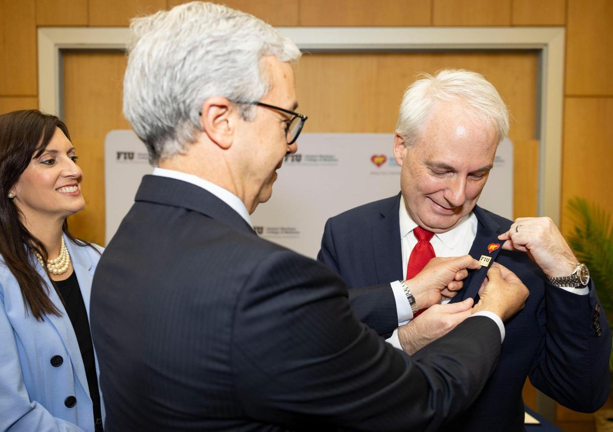 Dr. Juan Cendan, dean of FIU’s Herbert Wertheim College of Medicine, center, pins an FlU pin onto the lapel of Matt Love, president and CEO of Nicklaus Children’s Health System, right, while Jeanette Nuñez, interim president of FIU, watches during a ceremony announcing the launch of a new clinical, research and academic collaboration between FIU and Nicklaus Children’s Health System on Monday, May 19, 2025, at Florida International University campus in Miami, Fla.