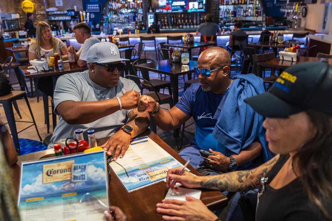 Passengers Derril Young, left, and Teryl Dixon sit at a bar after going through their checkpoint at Miami International Airport on the first day of REAL ID requirements on Wednesday, May 7, 2025.