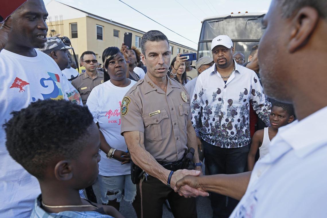 Juan Perez, Miami-Dade police director, salutes Terry Elliott, founder of community nonprofit Ark of the City at a peace walk held Wednesday, April 11, 2018, following recent shootings.