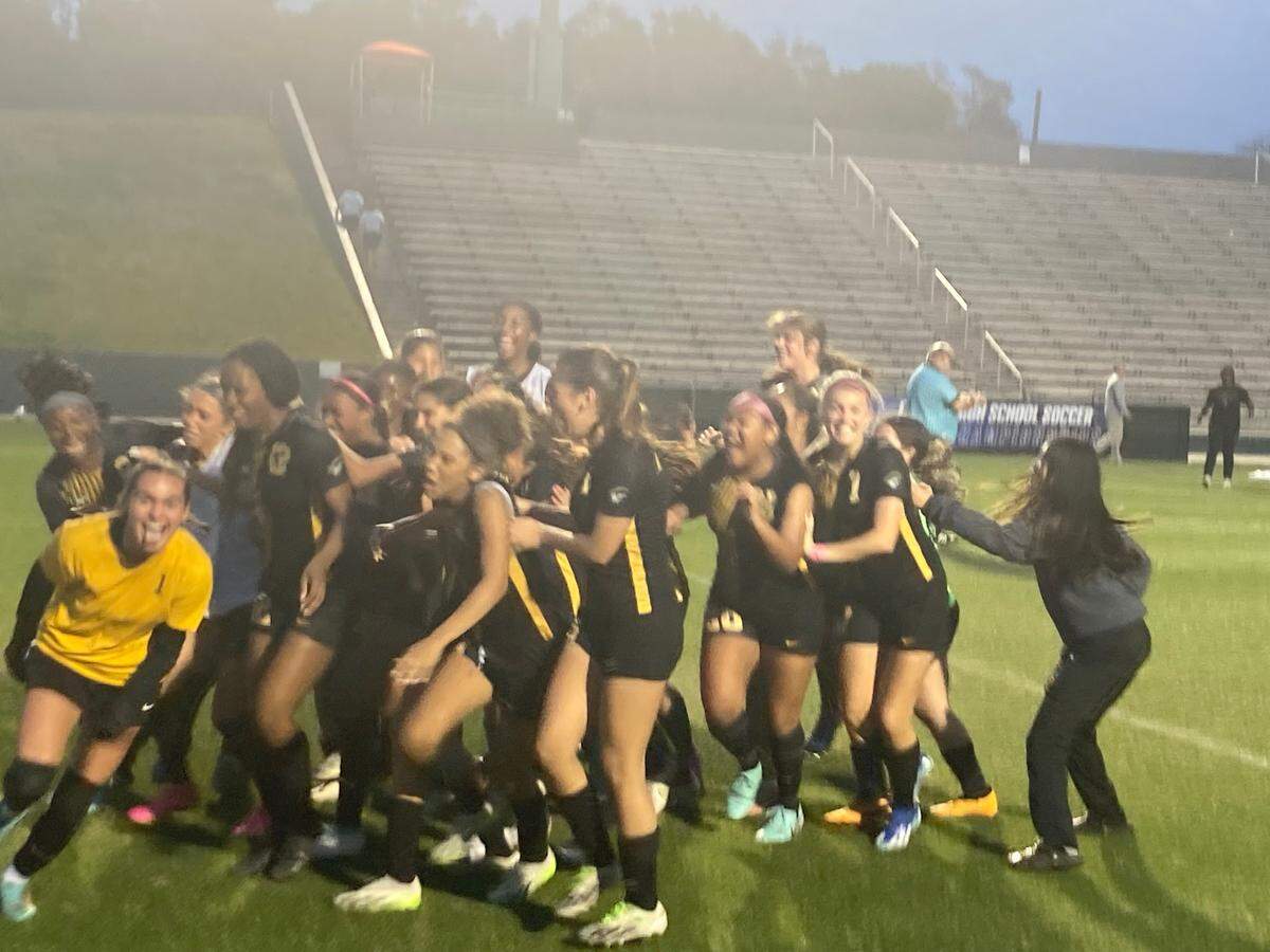 American Heritage goalkeeper Jillian Millfe (yellow jersey) storms toward her teammates just after making the winning save to clinch the Class 5A state championship on Friday at Spec Martin Stadium in DeLand, Fla.