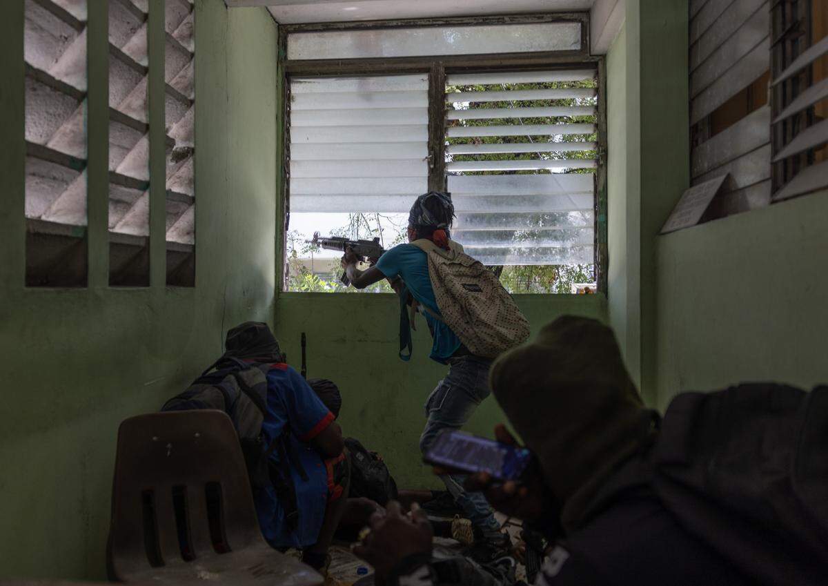 A gang member fires his rifle at police during a gun battle near the Presidential Palace Port-au-Prince on April 21, 2024.