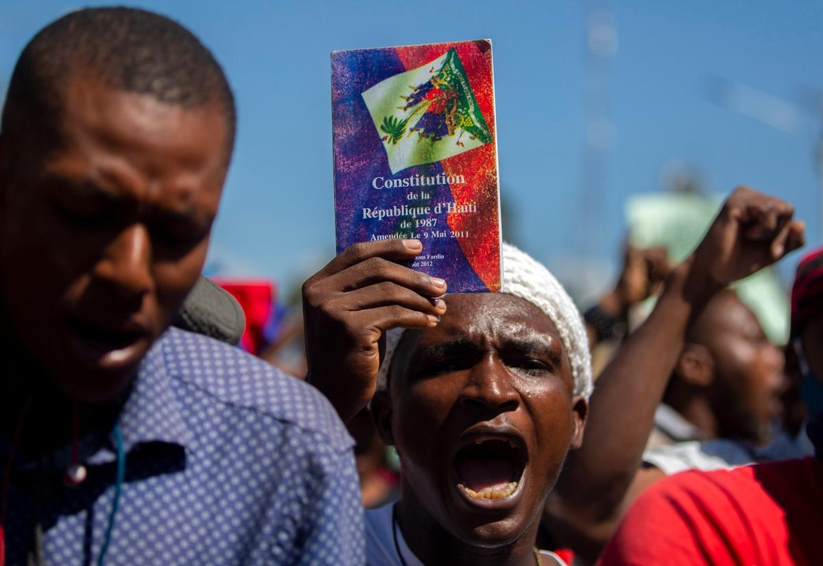 A protester holds up a copy of the Haitian constitution during a protest to demand the resignation of Haiti’s president Jovenel Moïse in Port-au-Prince, Haiti, Wednesday, Feb. 10, 2021. Haiti has lurched into a fresh political crisis amid allegations of a coup attempt and an escalating dispute over when the presidential term of Moïse should end.