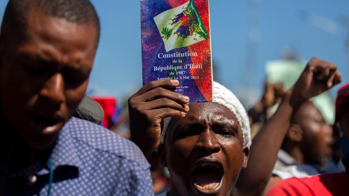 A protester holds up a copy of the Haitian constitution during a protest to demand the resignation of Haiti’s president, Jovenel Moïse, in Port-au-Prince, Haiti, Wednesday, Feb. 10, 2021. Haiti has lurched into a fresh political crisis amid allegations of a coup attempt and an escalating dispute over when the presidential term of Moïse should end.