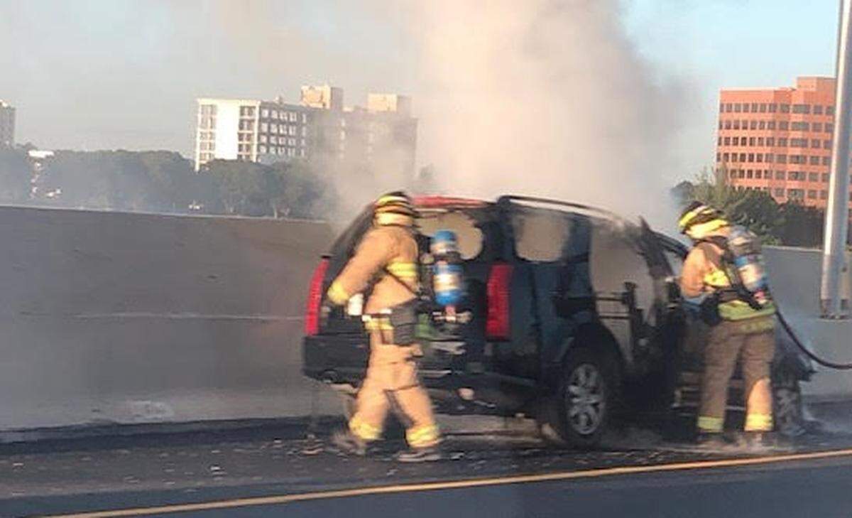 Firefighters working to put out the flames after a car caught fire on the Dolphin Expressway Tuesday morning.