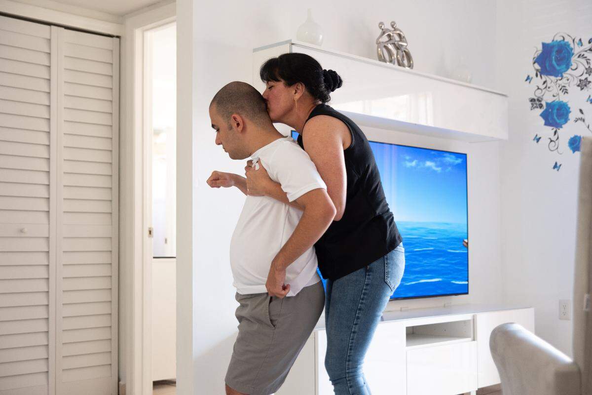 Yordanka Fernandez helping her son, Nicholas Katrib, walk to the bathroom of their Hialeah home.