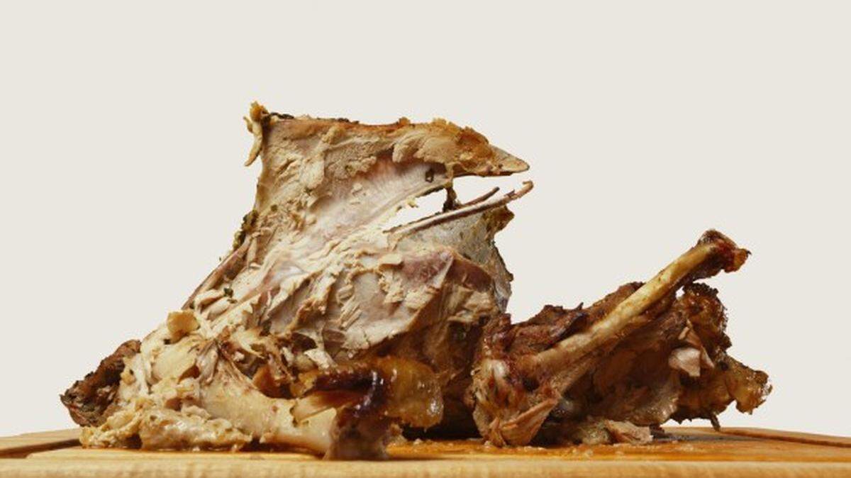 The remains of a roasted Thanksgiving turkey on a wooden cutting board.