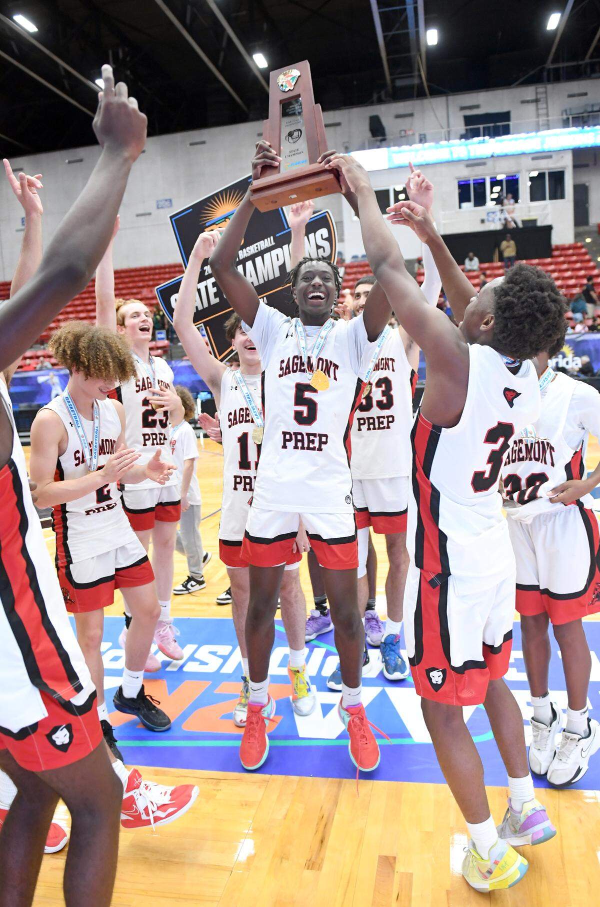 Sagemont’s Patrick Liburd (5) hoists the trophy as they celebrate their win over Orlando Christian Prep in the Class 2A final during the Florida High School State Championships at the RP Funding Center in Lakeland, Fl on Thursday February 29, 2024. Sagemont defeated Orlando Christian Prep 50-47.