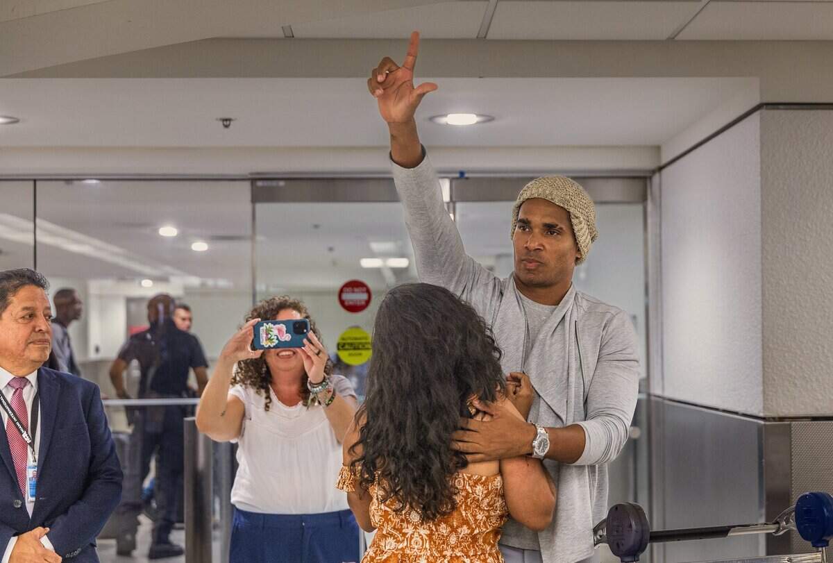 El artista disidente cubano Luis Manuel Otero Alcántara abraza a su amiga Anamely Ramos y hace un gesto de “libertad” con la mano al llegar al Aeropuerto Internacional de Miami el sábado.