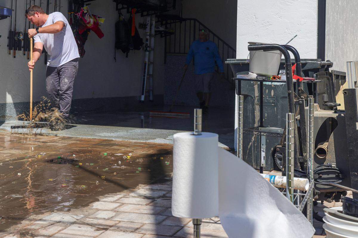 Cole Ondrejka sweeps muddy water out of his parent’s Buzzards Bay home at the entrance on Thursday, October 10, 2024, in Matlacha, Florida. 