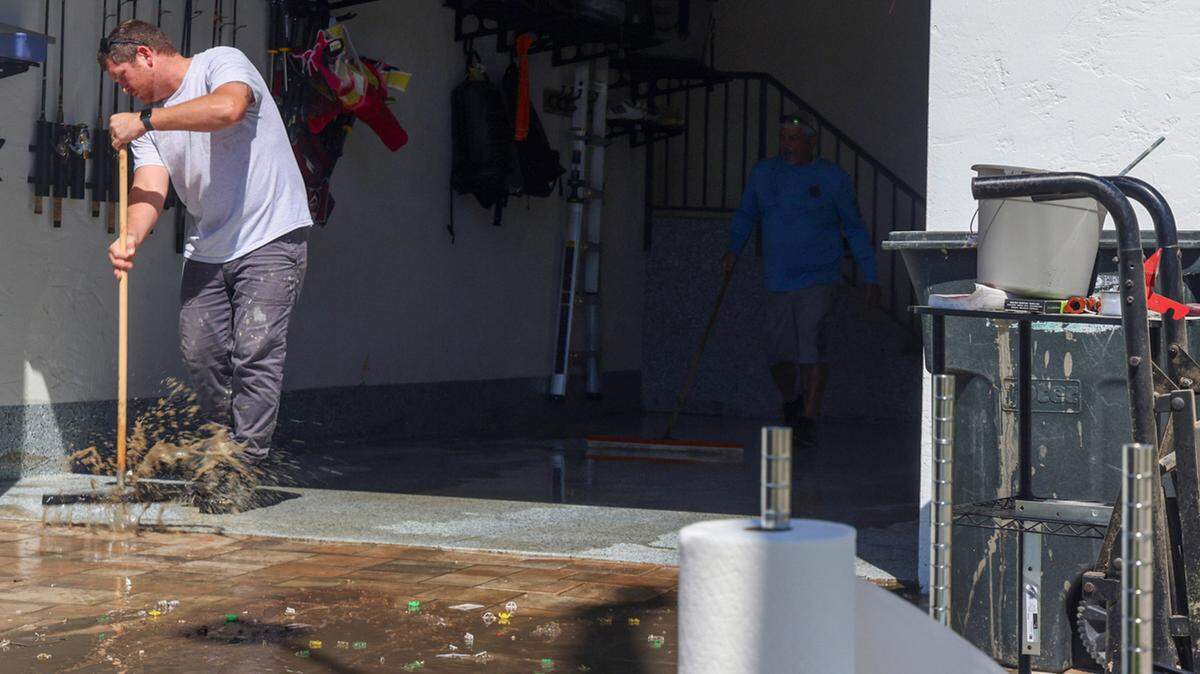 Cole Ondrejka sweeps muddy water out of his parent’s Buzzards Bay home at the entrance on Thursday, October 10, 2024, in Matlacha, Florida.